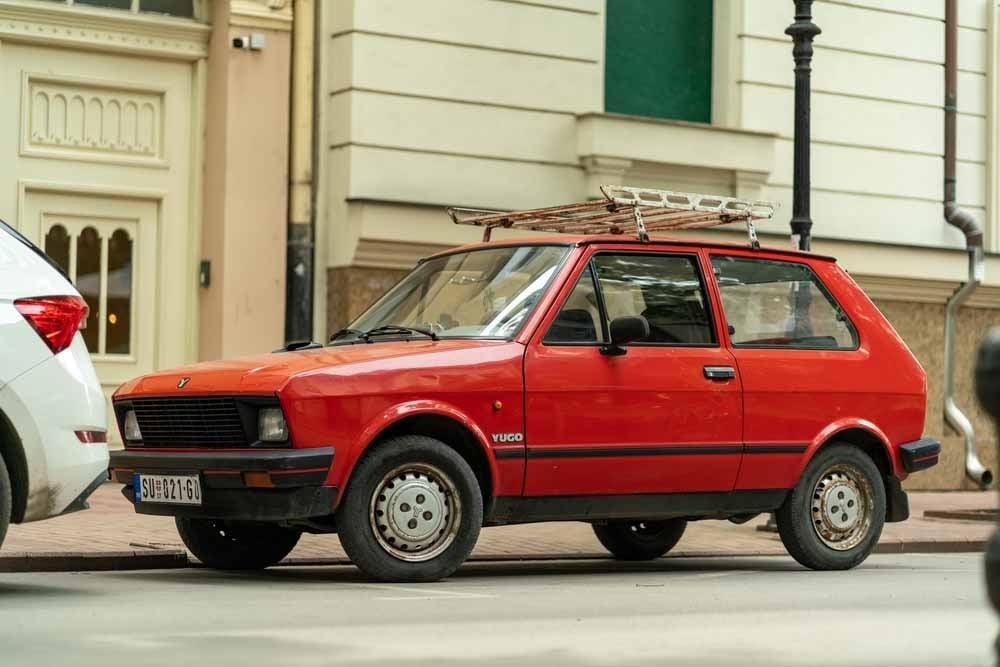 Yugo ile retro tur yapan bir grup, doğa ve eski kasaba manzarası